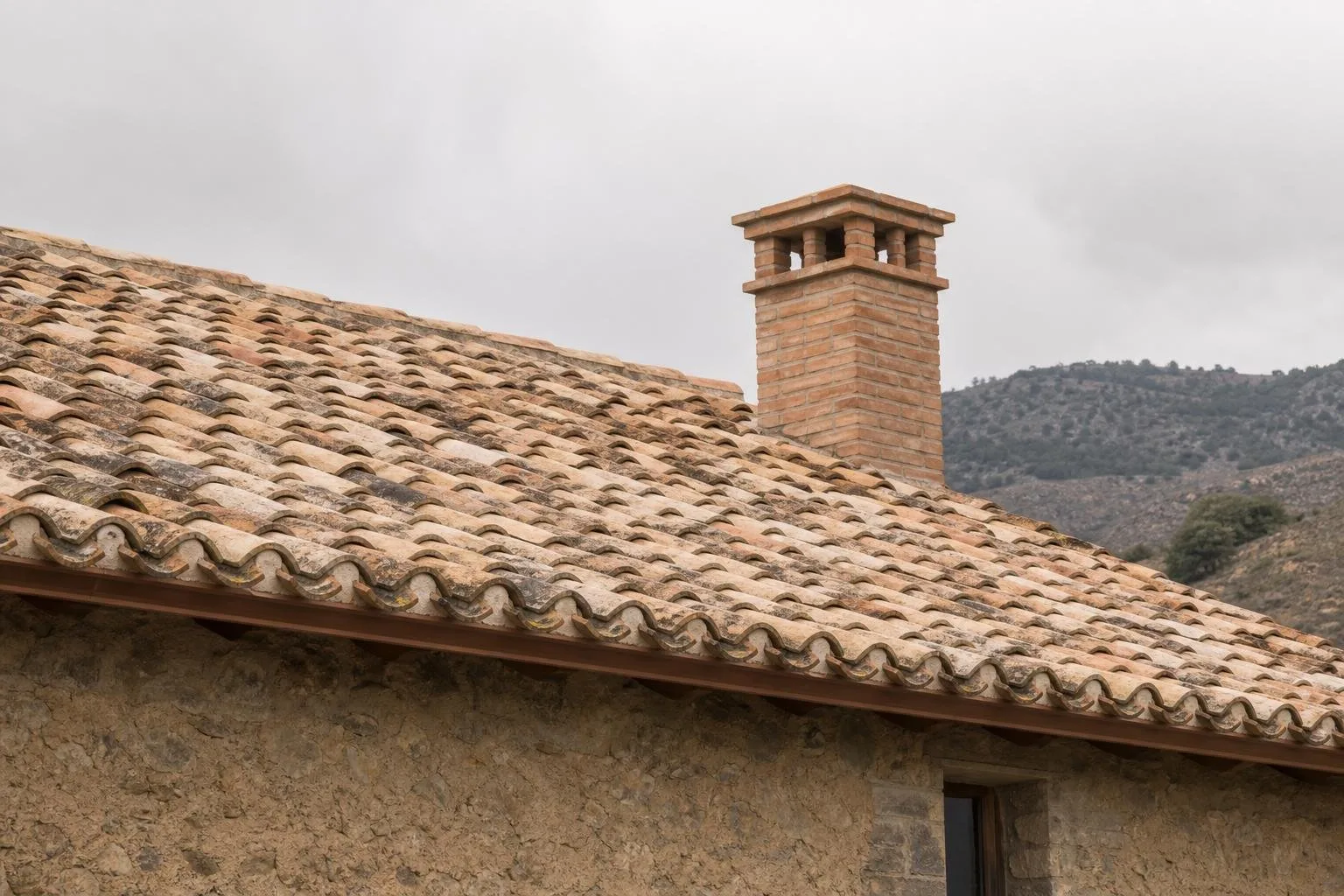Tejado de casa antigua restaurado con chimenea reconstruida