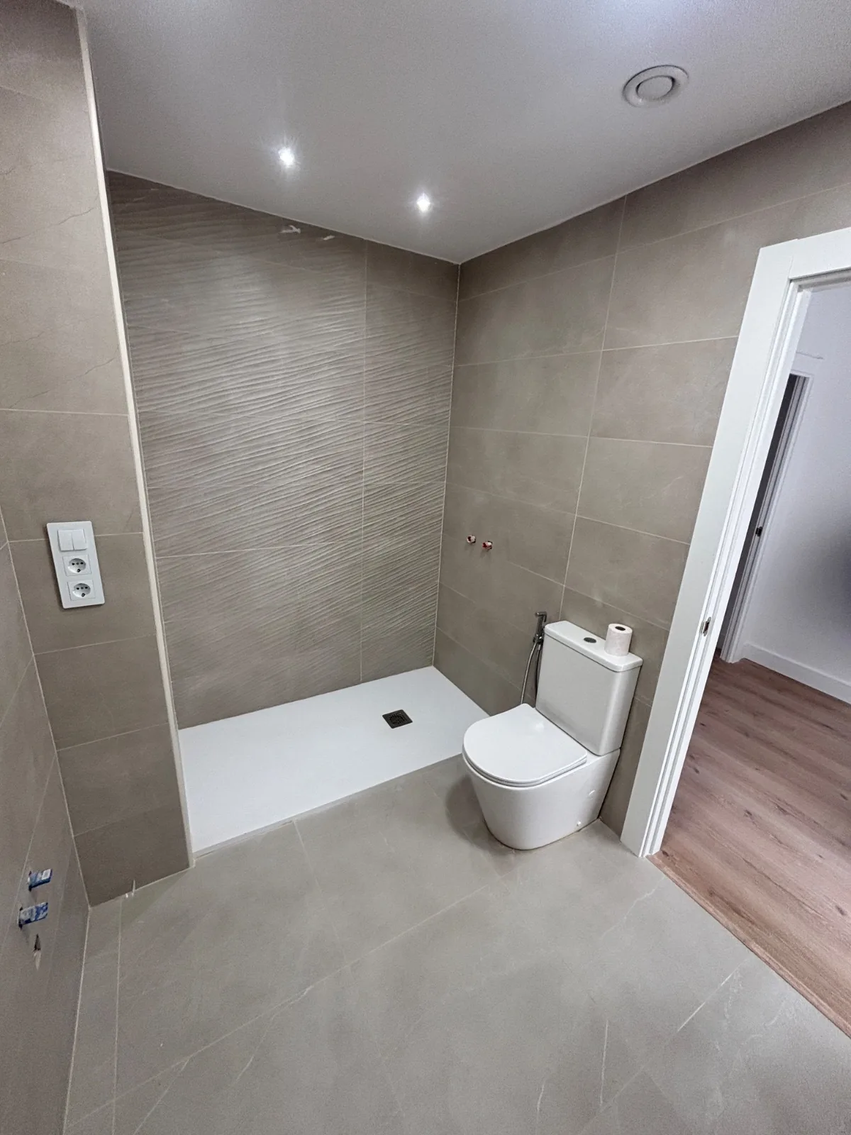 Baño reformado con plato de ducha a ras de suelo y azulejos gris pardo